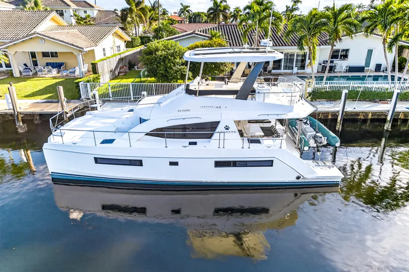  Yacht Photos Pics 2017 Leopard 43 Powercat yacht docked by waterfront homes, surrounded by palm trees.