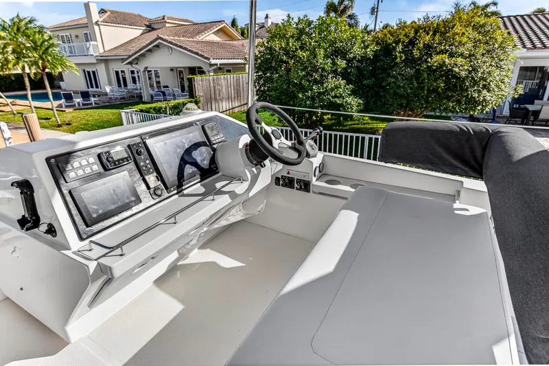  Yacht Photos Pics 2017 Leopard 43 Powercat helm with modern controls, docked near a luxurious waterfront home.