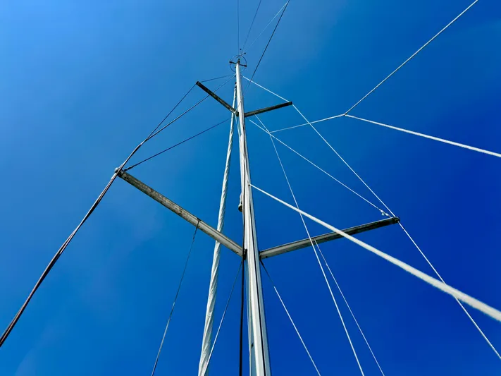 Glide Away Yacht Photos Pics Mast of 2015 Jeanneau Sun Odyssey 379 sailboat against clear blue sky.