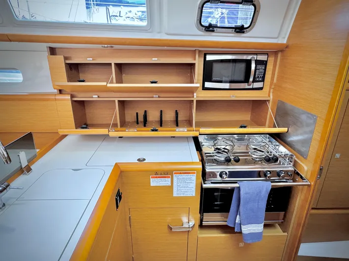 Glide Away Yacht Photos Pics Modern kitchen in 2015 Jeanneau Sun Odyssey 379 sailboat with stove, microwave, and storage.