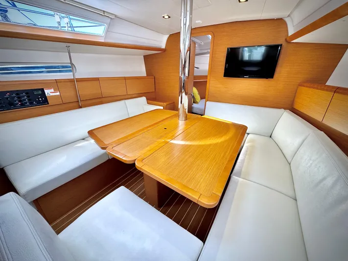 Glide Away Yacht Photos Pics Interior of 2015 Jeanneau Sun Odyssey 379 yacht with wooden table and white seating.