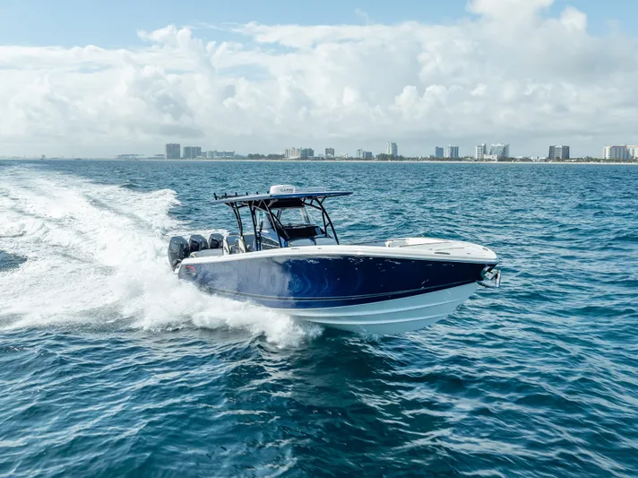 Work From Home Yacht Photos Pics 2024 Nor-Tech 390 Sport boat cruising on open water with city skyline in background.