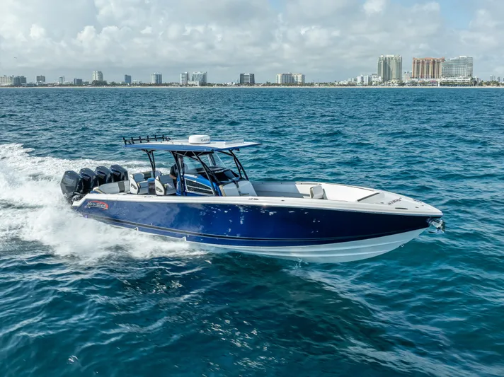 Work From Home Yacht Photos Pics 2024 Nor-Tech 390 Sport boat cruising on open water with city skyline in background.