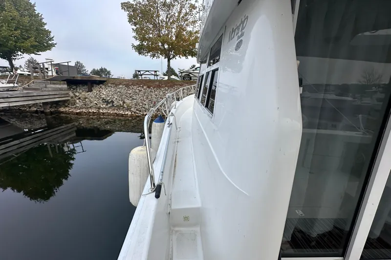 Lucky Dog Yacht Photos Pics 2002 Mainship 390 Trawler docked by a calm waterfront with trees in the background.
