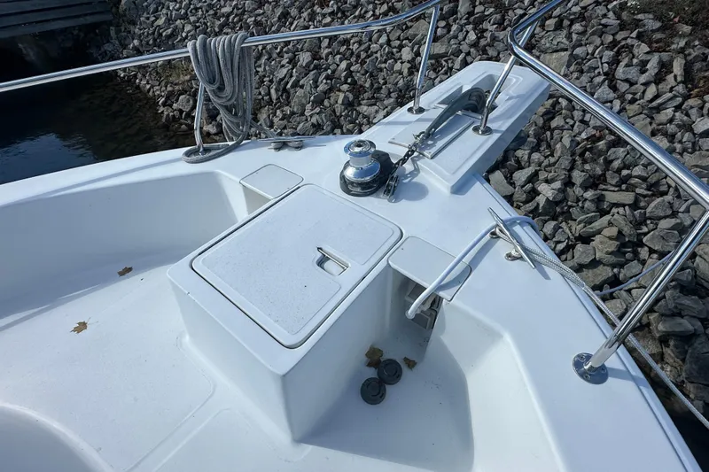Lucky Dog Yacht Photos Pics 2002 Mainship 390 Trawler bow with anchor, winch, and railing, docked by rocky shore.