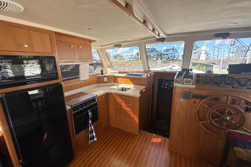 Lucky Dog Yacht Photos Pics Interior of 2002 Mainship 390 Trawler with kitchen and helm, featuring wood cabinetry and appliances.