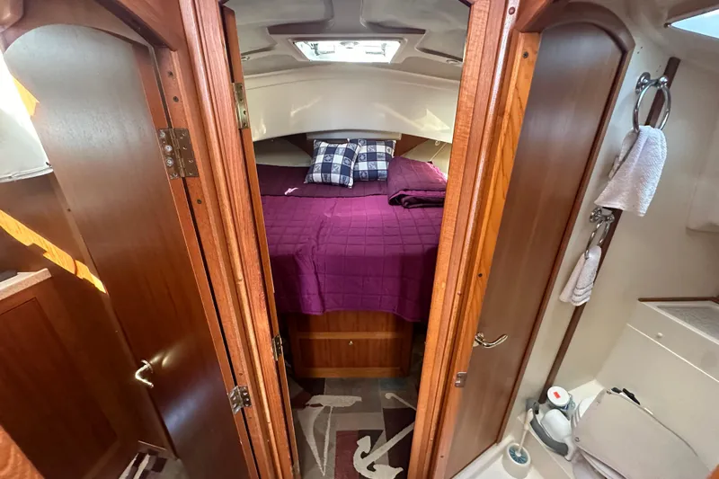 Lucky Dog Yacht Photos Pics Cozy cabin interior of 2002 Mainship 390 Trawler with purple bedding and wooden accents.