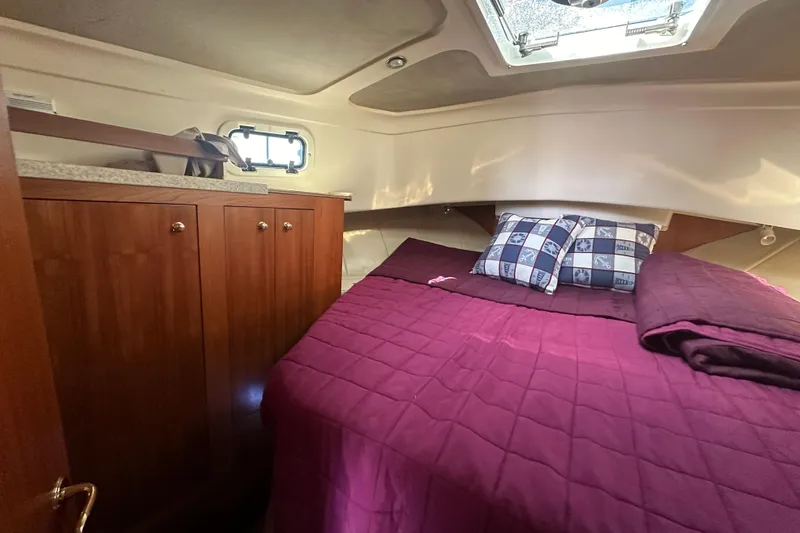Lucky Dog Yacht Photos Pics Cozy cabin interior of 2002 Mainship 390 Trawler with purple bedding and wooden cabinetry.