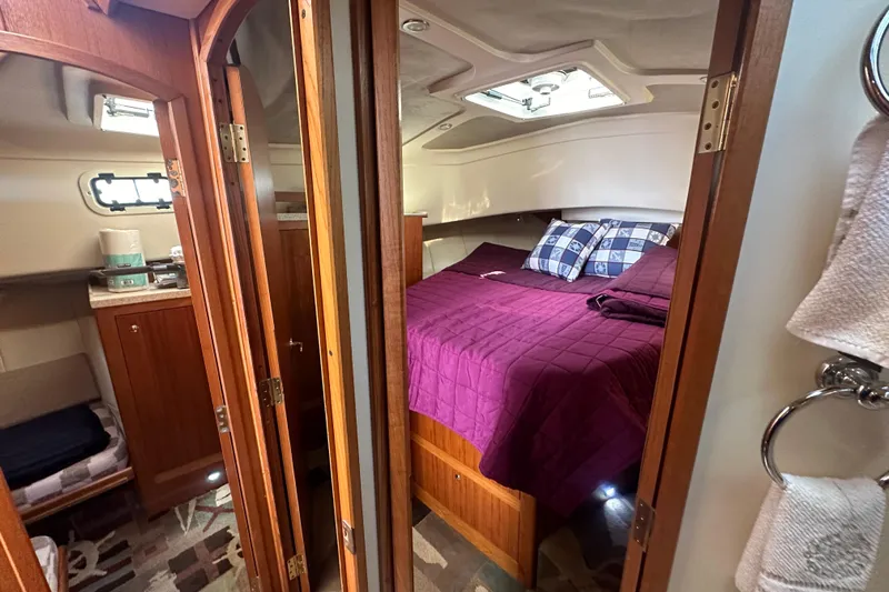 Lucky Dog Yacht Photos Pics Cozy cabin interior of 2002 Mainship 390 Trawler with purple bedding and wooden accents.