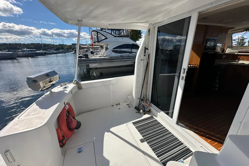 Lucky Dog Yacht Photos Pics 2002 Mainship 390 Trawler's deck with marina view, featuring sliding glass door and safety equipment.