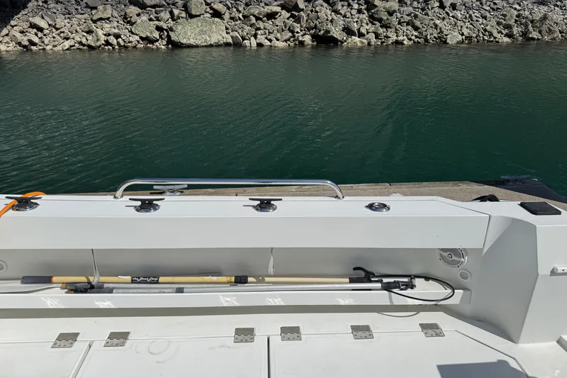  Yacht Photos Pics 2010 Ocean Sport Roamer boat docked by rocky shoreline, featuring a fishing rod holder.