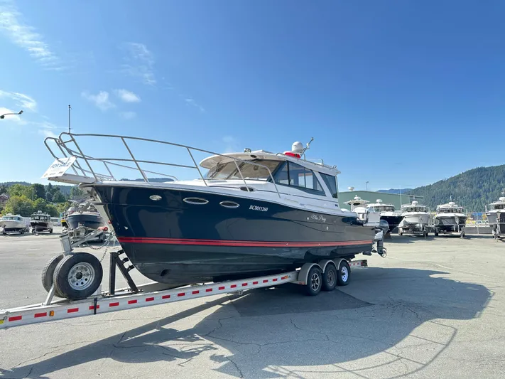  Yacht Photos Pics 2018 Cutwater C-302 Coupe boat on trailer, parked in marina under clear blue sky.
