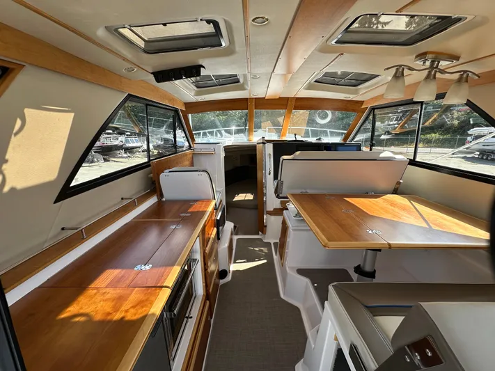  Yacht Photos Pics Interior of 2018 Cutwater C-302 Coupe boat with wooden tables and seating.