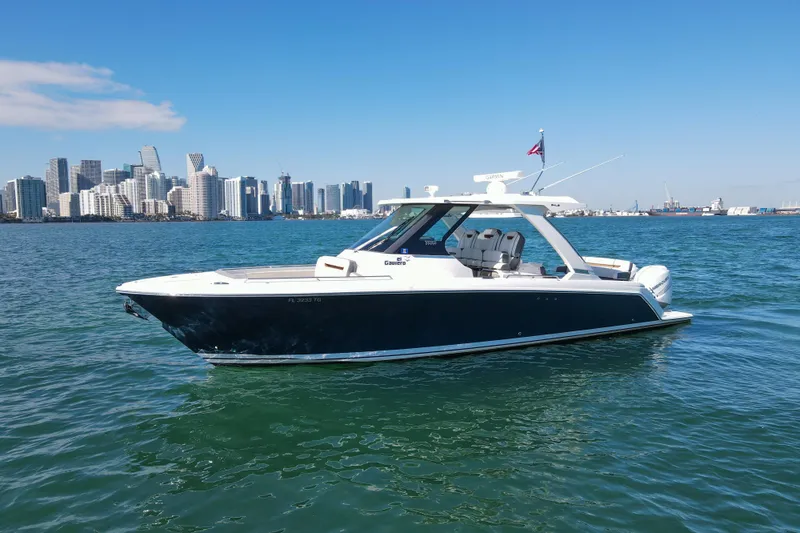  Yacht Photos Pics 2022 Tiara Yachts 34 LS cruising near city skyline on a sunny day.