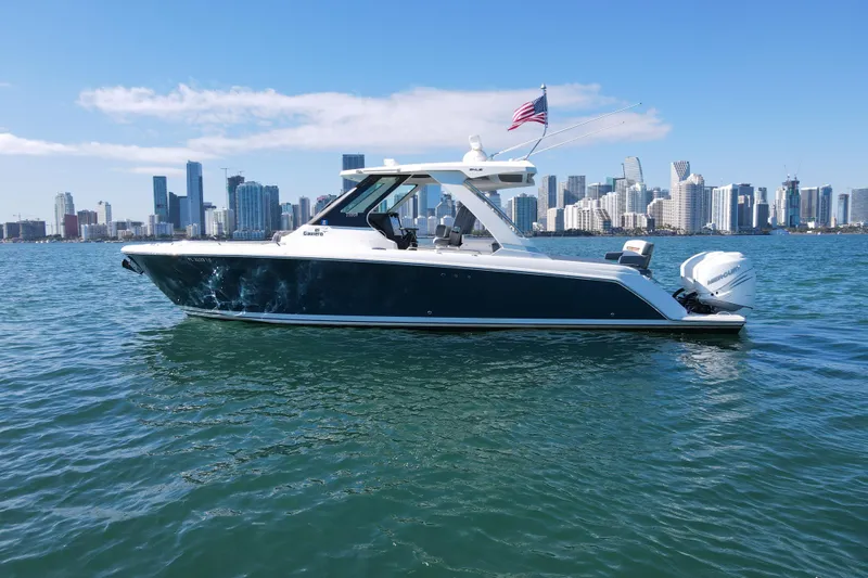  Yacht Photos Pics 2022 Tiara Yachts 34 LS cruising on water with city skyline backdrop.