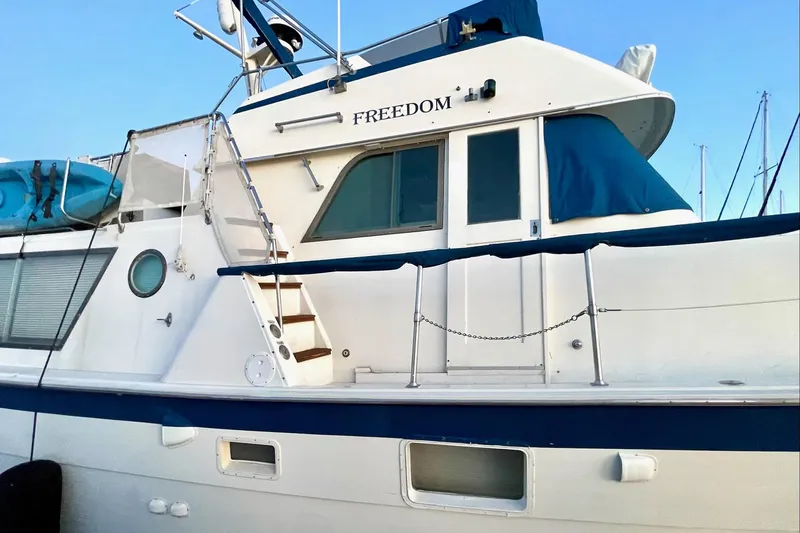 Freedom Yacht Photos Pics 1976 Hatteras 48 Long Range Cruiser yacht with blue accents and "Freedom" on the side.