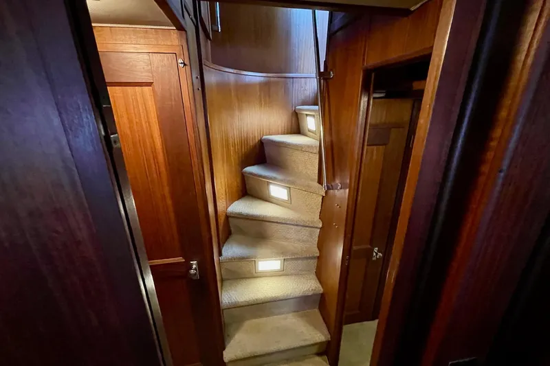 Freedom Yacht Photos Pics Interior staircase of 1976 Hatteras 48 Long Range Cruiser with wooden paneling and carpeted steps.