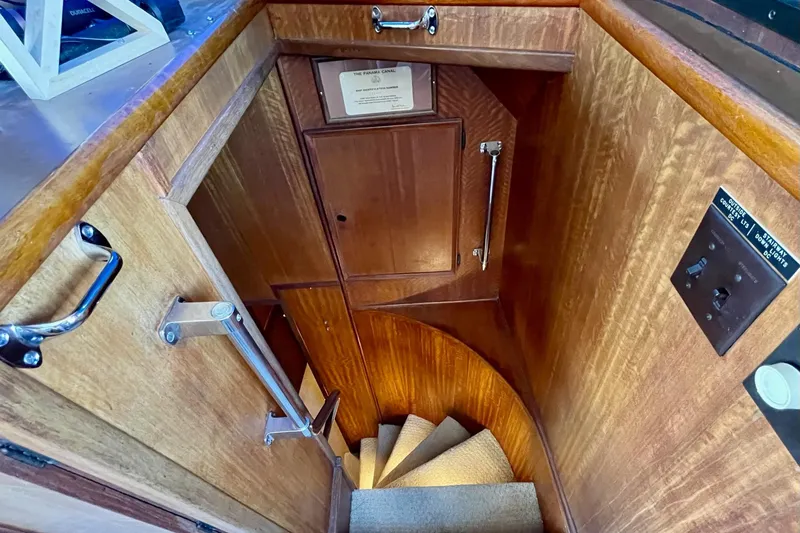 Freedom Yacht Photos Pics Interior staircase of 1976 Hatteras 48 Long Range Cruiser, featuring wooden paneling and carpeted steps.