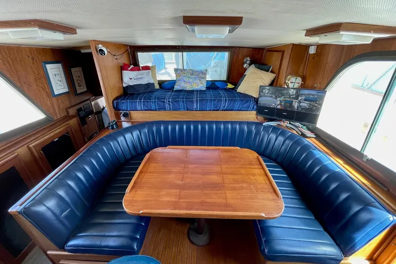 Freedom Yacht Photos Pics 1976 Hatteras 48 Long Range Cruiser interior with blue seating and wooden table.