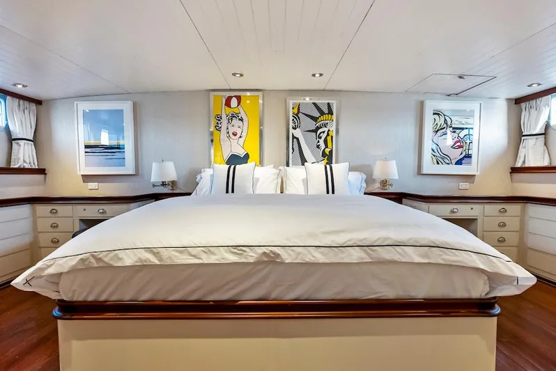 Chanticleer Yacht Photos Pics Luxurious yacht bedroom with modern art, white bedding, and elegant wood accents.