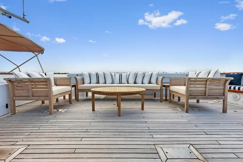 Chanticleer Yacht Photos Pics Spacious deck on 1973 Burger 310C yacht with wooden furniture and blue sky backdrop.