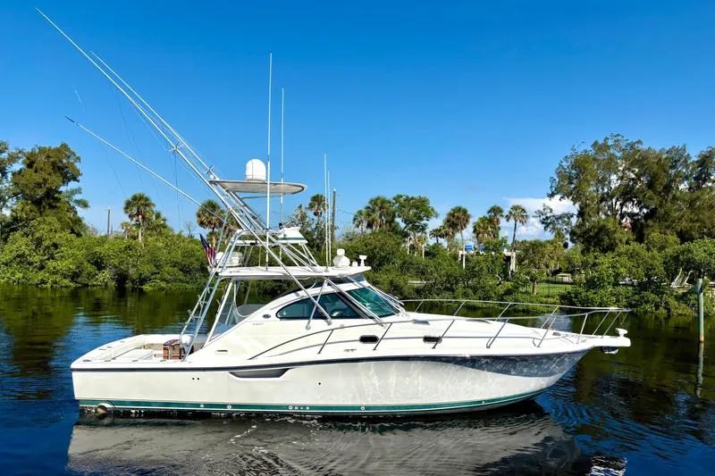 Kinja Yacht Photos Pics 2002 Pursuit 3800 Express boat on calm water with lush greenery background.