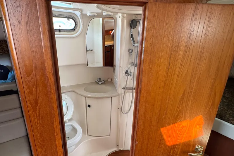 Kinja Yacht Photos Pics 2002 Pursuit 3800 Express yacht bathroom with sink, shower, and wooden door.