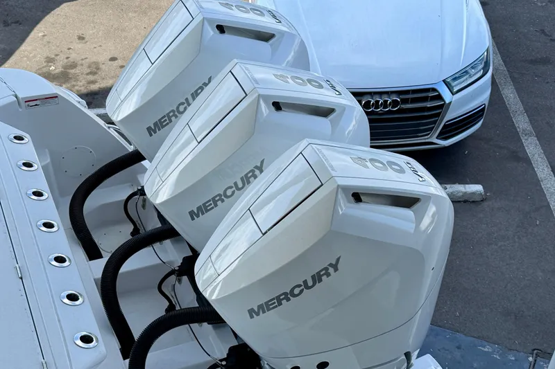  Yacht Photos Pics Three Mercury outboard engines on a 2026 Intrepid 375 Nomad SE, parked near a white car.