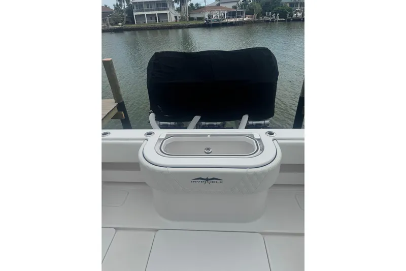  Yacht Photos Pics 2024 Invincible 39 Open Fisherman boat with covered engine, docked by waterfront homes.