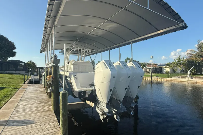  Yacht Photos Pics 2024 Invincible 39 Open Fisherman boat docked under canopy with triple outboard engines.
