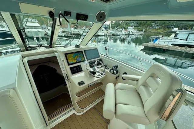  Yacht Photos Pics 2021 Boston Whaler 345 Conquest Pilothouse interior with helm, navigation screens, and marina view.