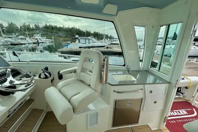  Yacht Photos Pics 2021 Boston Whaler 345 Conquest Pilothouse interior with helm, seating, and marina view.