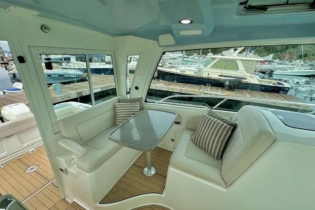  Yacht Photos Pics Interior of 2021 Boston Whaler 345 Conquest Pilothouse with seating and table, docked at marina.