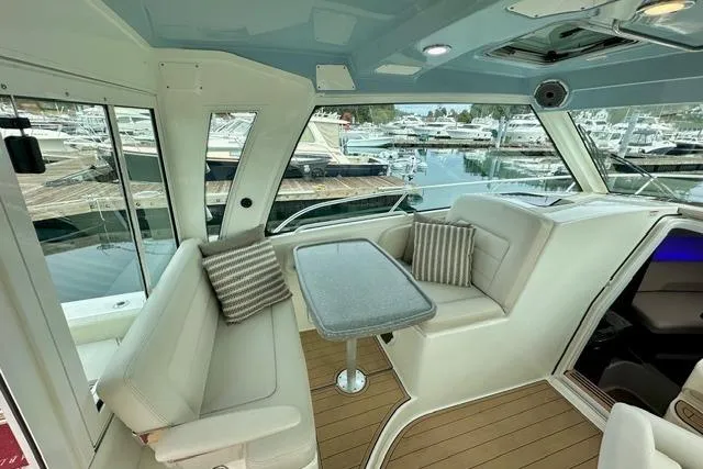  Yacht Photos Pics Interior of 2021 Boston Whaler 345 Conquest Pilothouse with seating and table, docked at marina.