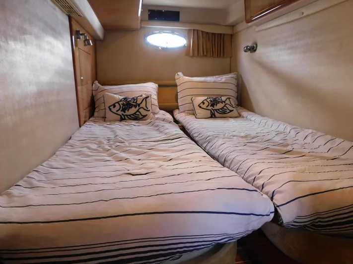 Sea Y'all Yacht Photos Pics Twin beds in a 2004 Regal Commodore 3860 cabin with striped bedding and fish-themed pillows.