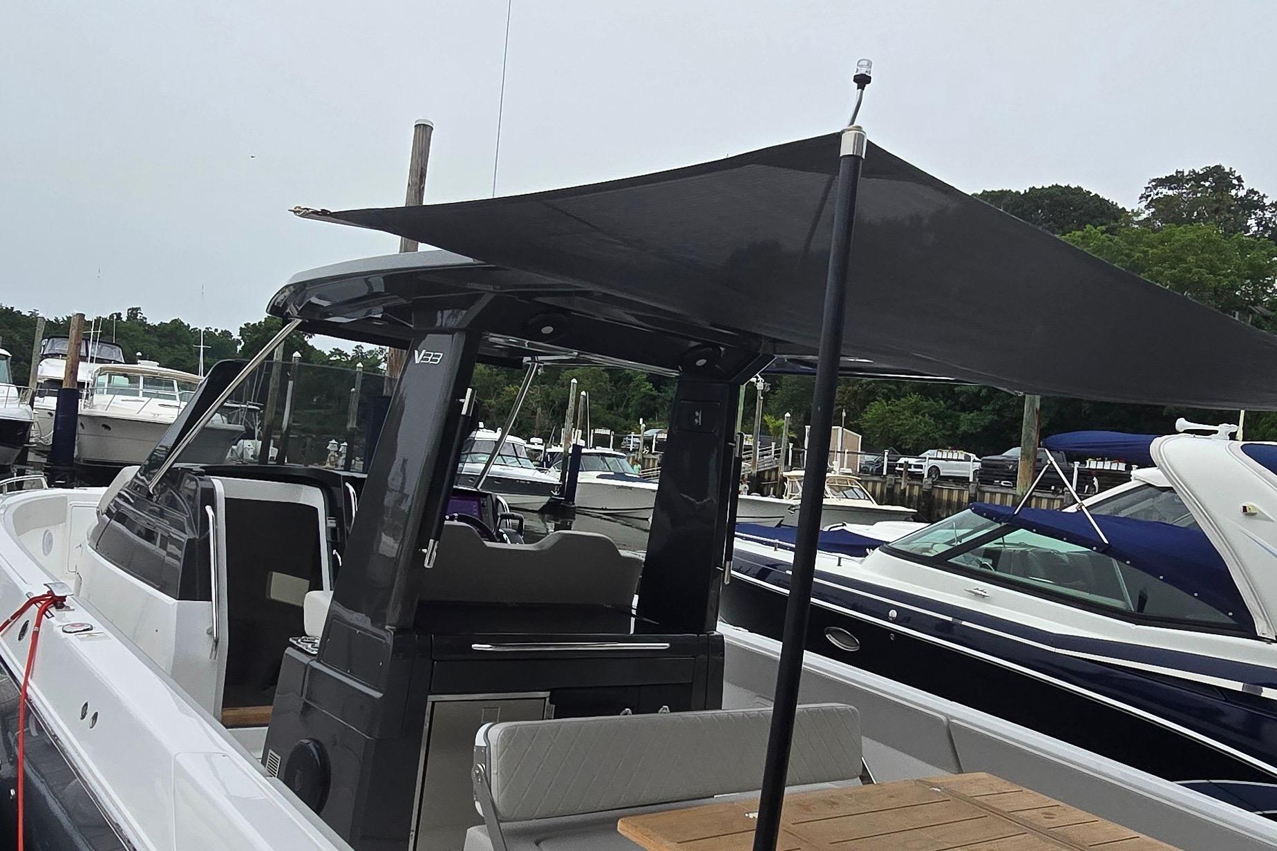 2025 Schaefer V33 boat with canopy, docked at marina with other boats.