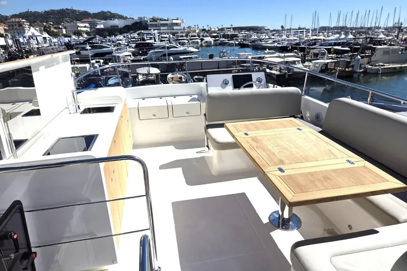 Menorquin 48 Fly Yacht Photos Pics 2026 Sasga Yachts Menorquin 48 deck with seating and table, docked at marina.
