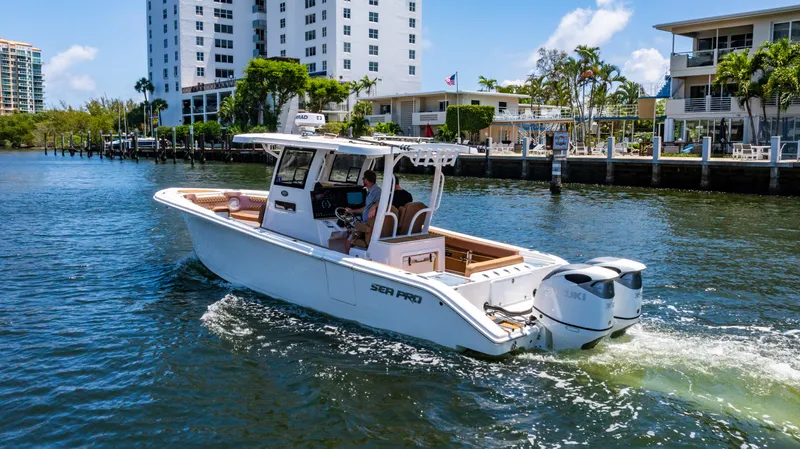  Yacht Photos Pics 2023 Sea Pro 320 DLX Offshore boat cruising on a sunny waterfront near modern buildings.