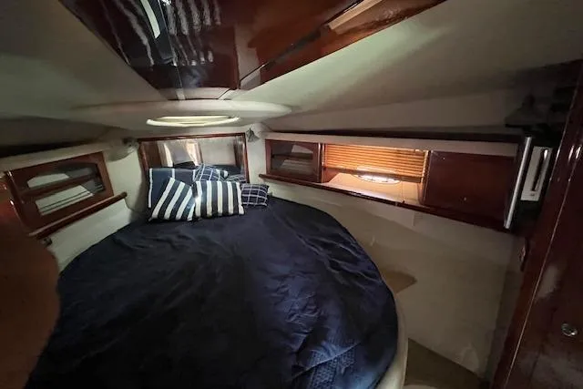  Yacht Photos Pics 2008 Doral Medditerra boat cabin with round bed, striped pillows, and wooden accents.