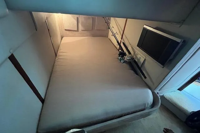  Yacht Photos Pics 2008 Doral Medditerra cabin interior with bed, fishing rods, and wall-mounted TV.