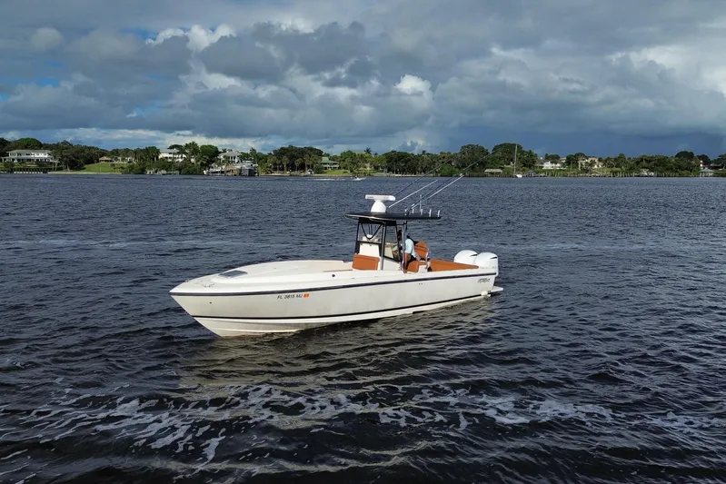  Yacht Photos Pics 2004 Intrepid 32 Cuddy boat cruising on a scenic waterway under cloudy skies.