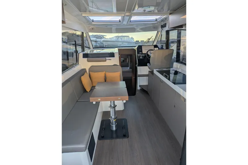  Yacht Photos Pics 2024 Beneteau Antares 11 interior with modern seating, table, and helm station.