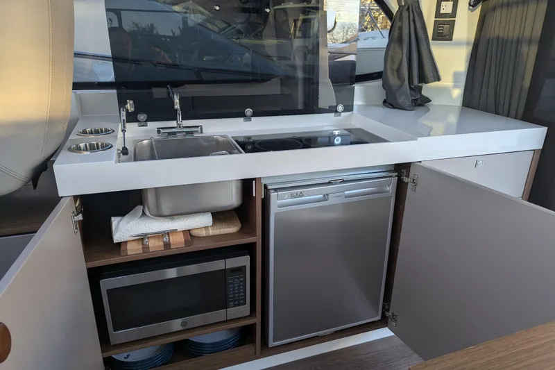  Yacht Photos Pics 2024 Beneteau Antares 11 kitchen with sink, stove, microwave, and fridge.