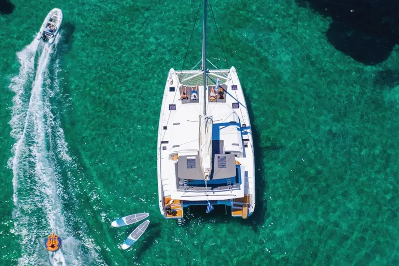  Yacht Photos Pics Aerial view of 2020 Dufour Catamarans 48 sailing on clear turquoise water.