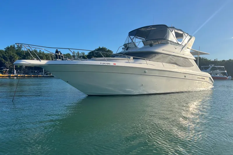  Yacht Photos Pics 1999 Sea Ray 440 Express Bridge yacht on calm water under clear blue sky.