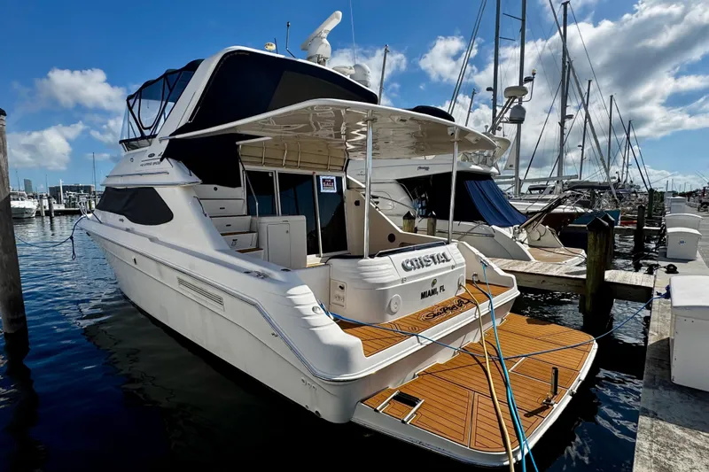  Yacht Photos Pics 1999 Sea Ray 440 Express Bridge yacht docked at marina under blue sky.