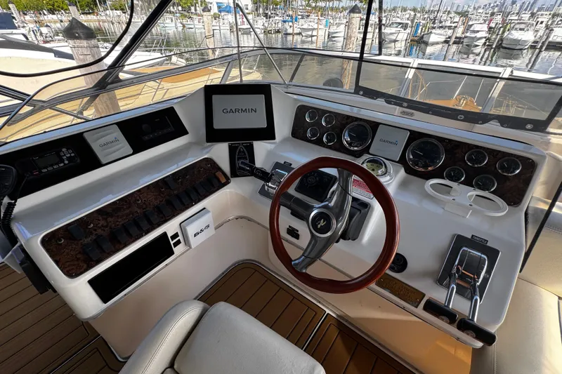  Yacht Photos Pics 1999 Sea Ray 440 Express Bridge helm with Garmin navigation, wood accents, and marina view.
