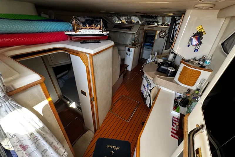  Yacht Photos Pics 1999 Sea Ray 440 Express Bridge interior with kitchenette, model ship, and wooden flooring.