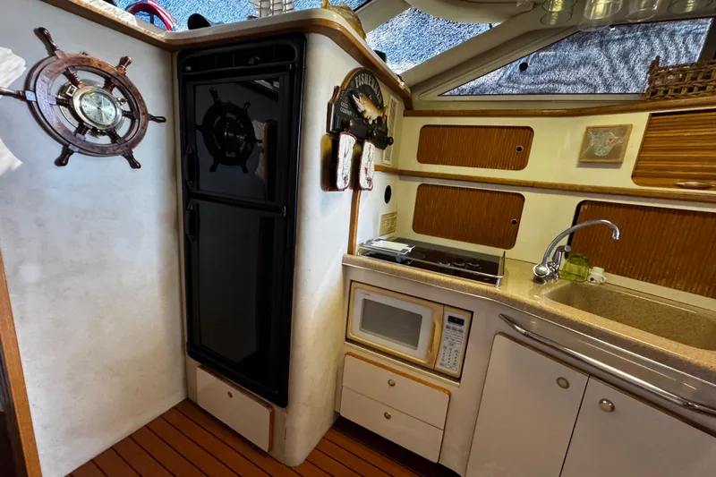  Yacht Photos Pics 1999 Sea Ray 440 Express Bridge kitchen with microwave, sink, and nautical decor.