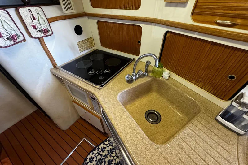  Yacht Photos Pics 1999 Sea Ray 440 Express Bridge kitchen with stove, sink, and wooden cabinetry.